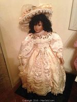 Front view of Lady Jennifer porcelain doll in detailed cream dress and large hat showing lace and fabric textures.