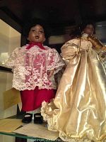 Two dolls on display: the Hearts in Song Grace doll in gold dress with violin and angel doll in pink lace outfit.