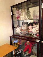 Front view of the two-piece display cabinet set containing figurines inside, showing glass panels and mirrored back