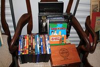 DVDs and cigar boxes placed on a wooden chair showing various DVD titles and wooden boxes