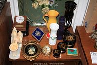 Wide view of vintage decorative items on wooden table including clock, bookends, vases, lacquer boxes, plaques, and tray