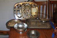 View of all trays, bowls, and wire basket together on table showing size, shape, and markings