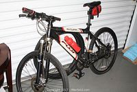 Full side view of Fuji Outland Pro-Series mountain bike showing red and black frame, front suspension fork, water bottle, pedals and tires.