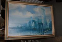 Full view of framed oil painting depicting New York City skyline with the Twin Towers and Brooklyn Bridge under a partly cloudy sky.