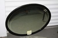 Full view of the oval black wood frame mirror placed against a white background, showing overall shape and condition.