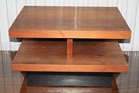 Front view of the rectangular two-tier side table showing walnut veneer top and middle shelf with vertical support panel and black base.