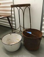 Photo of antique metal frame stool with walnut stained seat and two buckets, one rusted metal and one white enamel.