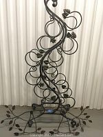 Front view of wrought iron style wine rack showing circular holders and leaf accents.