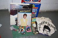 Wide shot showing all items including Michael Jackson vinyl records, calendar, buttons, patches, t-shirt and two baseball card guides