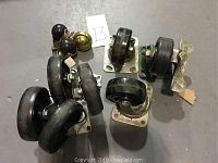 Photo showing 10 assorted swivel casters with various sizes and some brass-colored items on a grey floor.