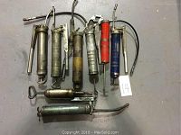 Overview of 8 industrial grease guns showing variety of cartridge colors, lever types, and spouts