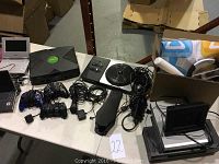 Overview of all the listed items including Xbox, controllers, portable DVD players, Guitar Hero accessories, Wii mat, electronic picture frame, DVD and VHS players.