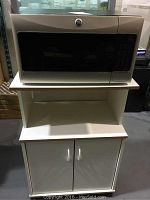 Front view of GE microwave on white storage stand cabinet