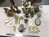 Overview of all 18 angel and fairy figurines and plaques arranged on a table.