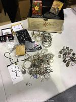 Wide view of lot showing assorted jewelry including rings, bracelets, multiple box containers, and necklaces gathered on table.