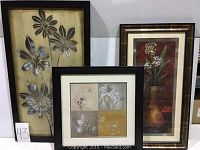 Lot of 3 framed pictures including one large metal floral wall art and two smaller floral prints.