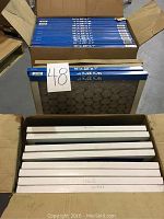 Box of 24 furnace filters, 16 filters sized 16x25x1 inch stacked in upper part of box and 8 filters sized 16x20x1 inch stacked below.