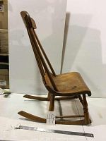 Side view of vintage wooden rocking chair showing curved seat, turned legs, and rockers. The low seat height is visible.