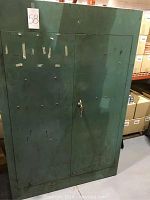 Front view of closed green steel two-door cabinet with key lock