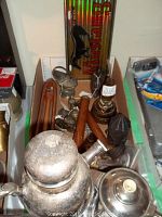 Front view of several vintage metal and glass collectible items including the silverplate cocktail server and wool loom shuttle in a box.