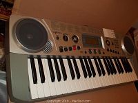 Front angled view of Nextech electronic keyboard showing keys, speakers, control knobs, buttons, and display screen.