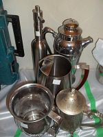 Photo shows a stainless steel pepper grinder, engraved stainless steel cocktail server, silverplate tea server with tarnish, and a large chrome cream sugar server with open rim and handle.