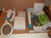 Two Nintendo Wii systems with multiple accessories including tennis racket, remotes, and new Wii Fit Protect Kit pack.