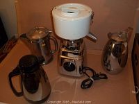 Juicer and three coffee pots on countertop showing overall condition and size comparison.
