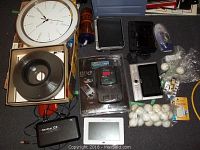 Full lot overview showing all items including golf accessories, electronics, clock and VHS tapes.
