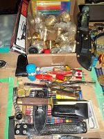 Overview showing wooden lures, knives with sheaths, watches, colored pencils packages, and brass candle holders.