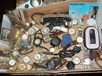 Box containing a variety of wristwatches, watch bands, chargers, and accessories