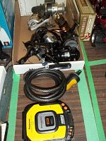 Three fishing reels in a box with a coiled cable bicycle lock and a Panasonic portable CD player on table surface.