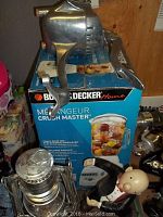 Photo of Wear-Ever aluminum handheld juicer on top of Black and Decker Crush Master blender box.