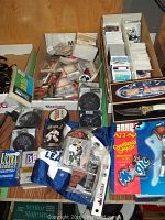Overview of lot showing various sports cards, hockey pucks, Maple Leafs flag, Molson hockey stick blade, collectible knife in package, and Shaq figure in package.