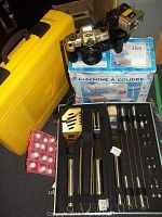 Full view of the lot showing barbecue set, Canon camera on sewing machine box, thimble set, and yellow laser level case