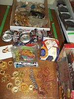 Display of various small items including pop can miniature vehicles, assorted jewelry chains, chandelier crystals and packaged musical display.