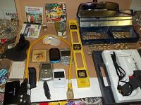Wide angle photo showing the collection of tools, level, extension cord, cell phones, and drill bit case.