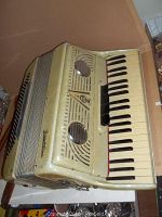Front view of the cream-colored Frontalini accordion showing keyboard and front grille with circular speakers.