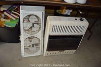 Eastern Electric twin window fan and Charmglow heater side by side on the floor with background items visible.