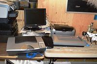 Work area showing Balance 15 inch TFT LCD monitor model CM2015 centered on a shelf with Lexmark printers and cables nearby.