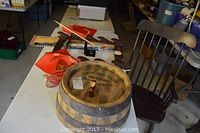 Photo showing wooden wall sword rack with one sword, Marine Corps flags and barrel, and wooden rocking chair