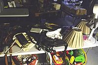 Table covered with various purses, lamp shades, and white gooseneck table lamp visible on right side.