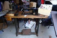 Wide view showing both sewing machines with accessories and wooden case on the side.
