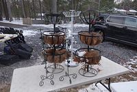 Two three-tier metal outdoor planters with coco fiber liners on white table with snowy background