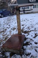 Full view of antique platform scale showing the rusted metal platform and vertical arm.