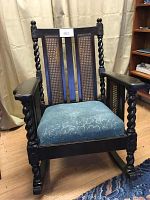 Front view of Victorian rocking chair showing twisted spindle arms, cane panels on backrest, and upholstered seat.
