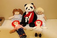 Shows the entire set of dolls and plush bears including the two Cabbage Patch Dolls, Raggedy Ann and Andy dolls, and the large and small Gund panda bears.