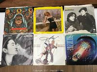 Top view of six 45 RPM record sleeves featuring Blue Oyster Cult, Blondie, Beautiful Boys, John Lennon & Yoko Ono, Dolly Parton, and Fuzzbox.
