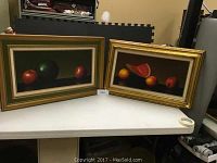 Both framed paintings side by side on tabletop