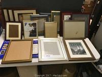 Photo showing 18 mixed picture frames on a table, various sizes and colors visible.